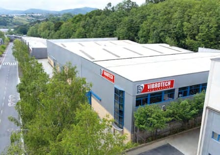 Vibrotech manufacturing facility exterior with company logo, surrounded by trees and industrial setting, representing high-performance machinery for foundries.